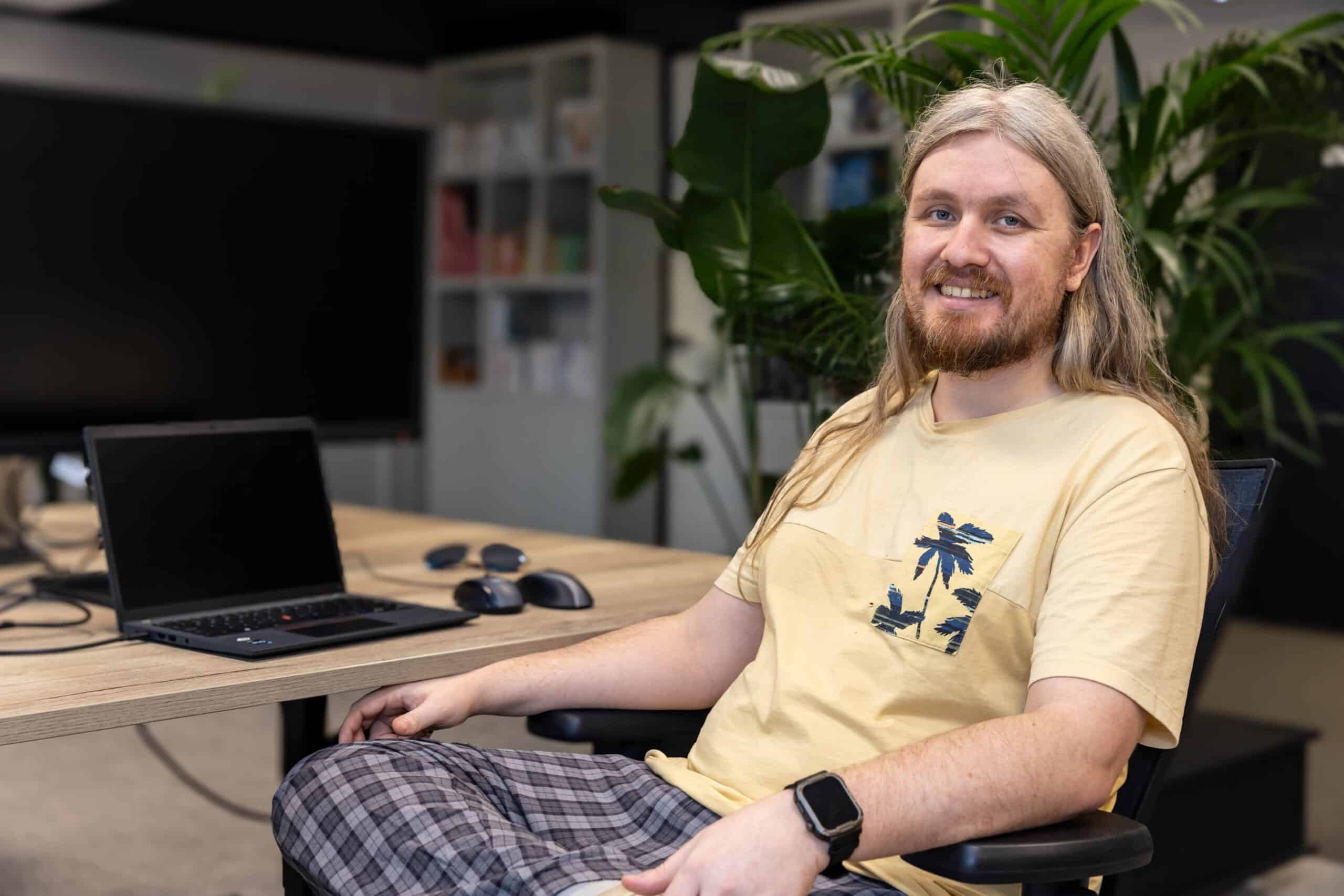 Buitengewoon talent Ben Jones aan zijn bureau achter zijn laptop, terwijl hij omgedraaid zit
